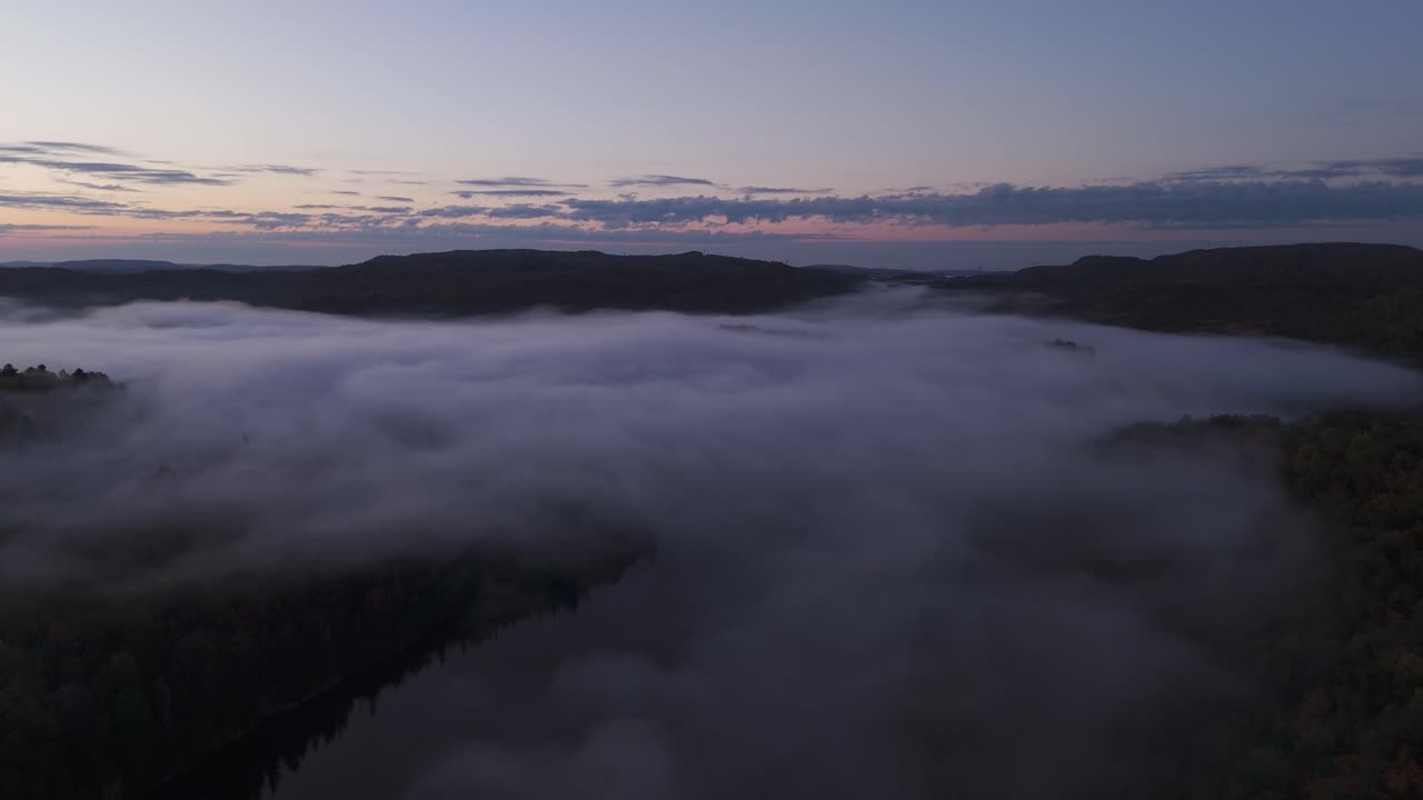 drone above sea of clouds in a foggy misty landscape at sunset , aerial of forest in nature