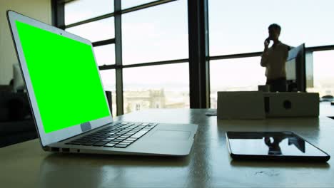 computadora portátil y tableta digital en la mesa mientras la mujer de negocios habla por teléfono móvil 4k