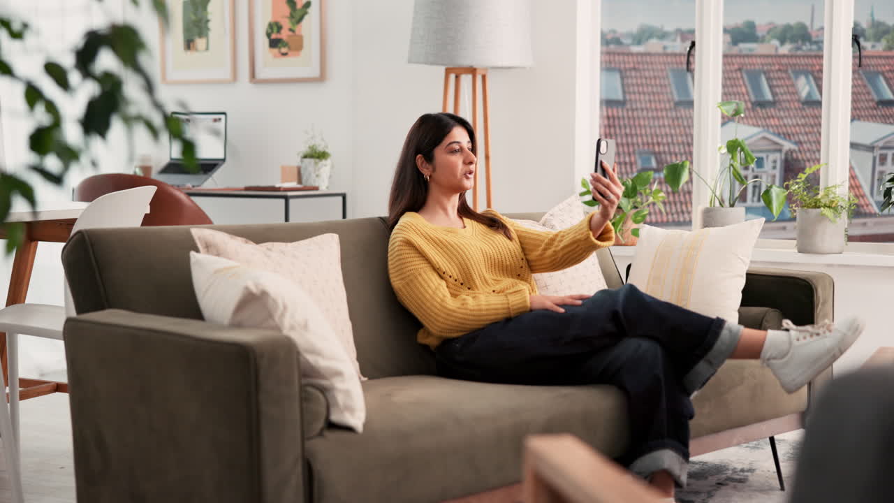 Donna seduta sul divano che parla al telefono