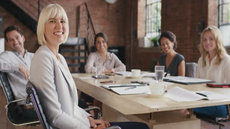 portrait of a confident young business woman  at boardroom table in slow motion turning around and smiling