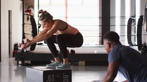 video of fit caucasian woman jumping on block at gym