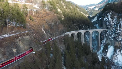 excellent aerial view of a train passing along the landwasser viaduct in switzerland