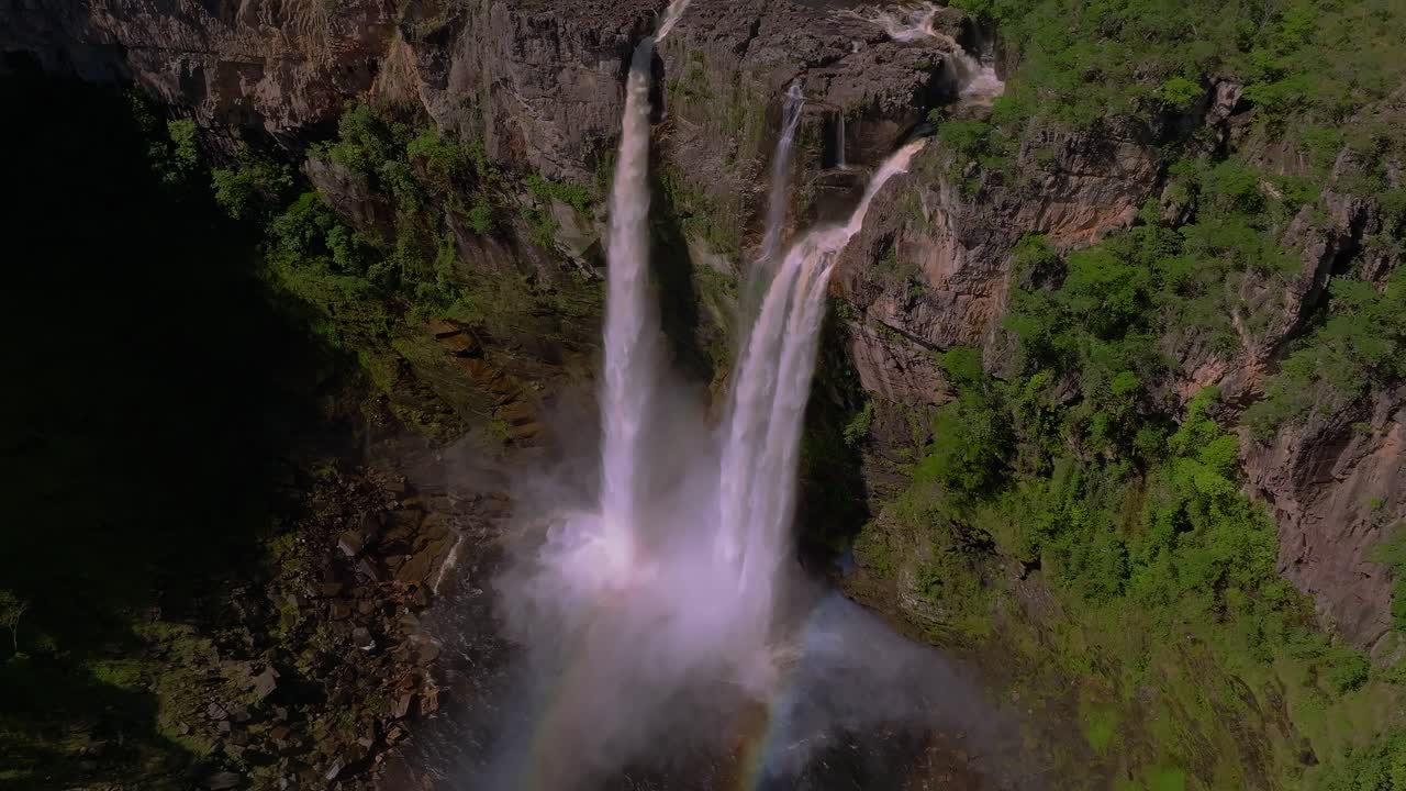 Cachoeira dos Saltos waterfall plunging into a pool, creating a rainbow in the mist, amidst the lush greenery of Chapada dos Veadeiros National Park, a UNESCO World Heritage site in Goiás, Brazil