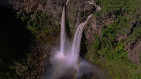 cachoeira dos saltos waterfall plunging into a pool, creating a rainbow in the mist, amidst the lush greenery of chapada dos veadeiros national park, a unesco world heritage site in goiás, brazil
