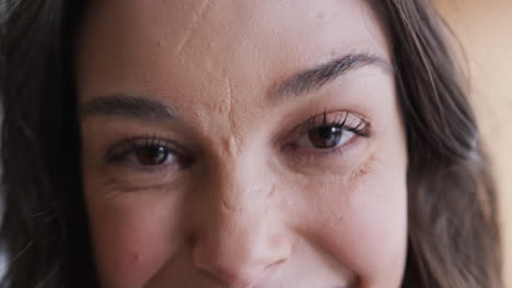 los ojos de una feliz mujer caucásica de pie y sonriendo en un hogar soleado, en cámara lenta.