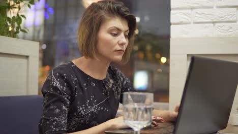 young business woman sitting in a cafe with a laptop and working