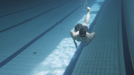 Toma-Submarina-De-Una-Joven-Nadadora-Buceando-En-Una-Piscina-En-Dirección-A-La-Cámara