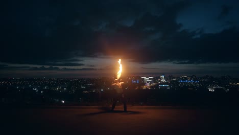 Young-blond-male-does-tricks-with-fire-breaths-fireball-in-the-middle-of-the-night-with-city-skyline-2