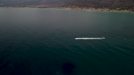 Drone-tilt-shot-of-a-fast-sailing-Jetski-near-the-coast-of-Chersonissos-at-Crete