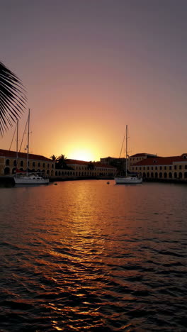 sunset over a harbor with boats and buildings
