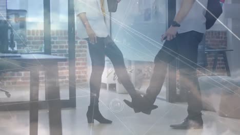 network of connections against diverse office colleagues greeting by touching feet at office