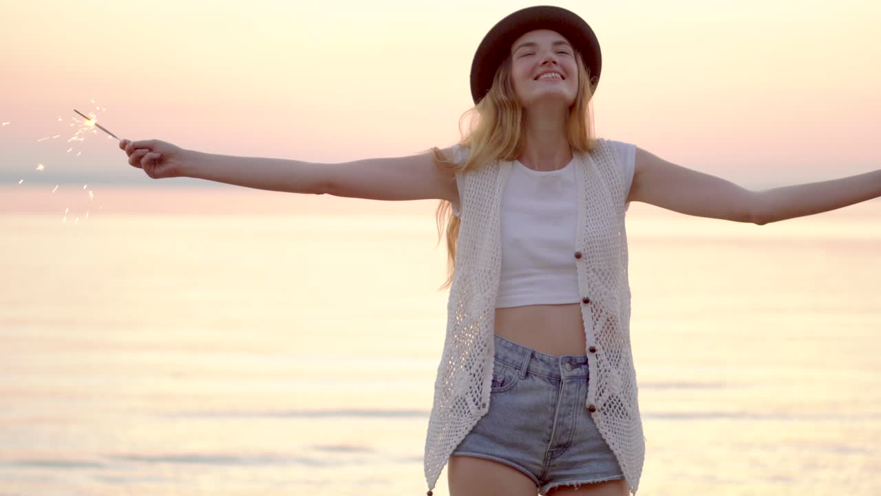 Woman with sparklers on the beach at sunset