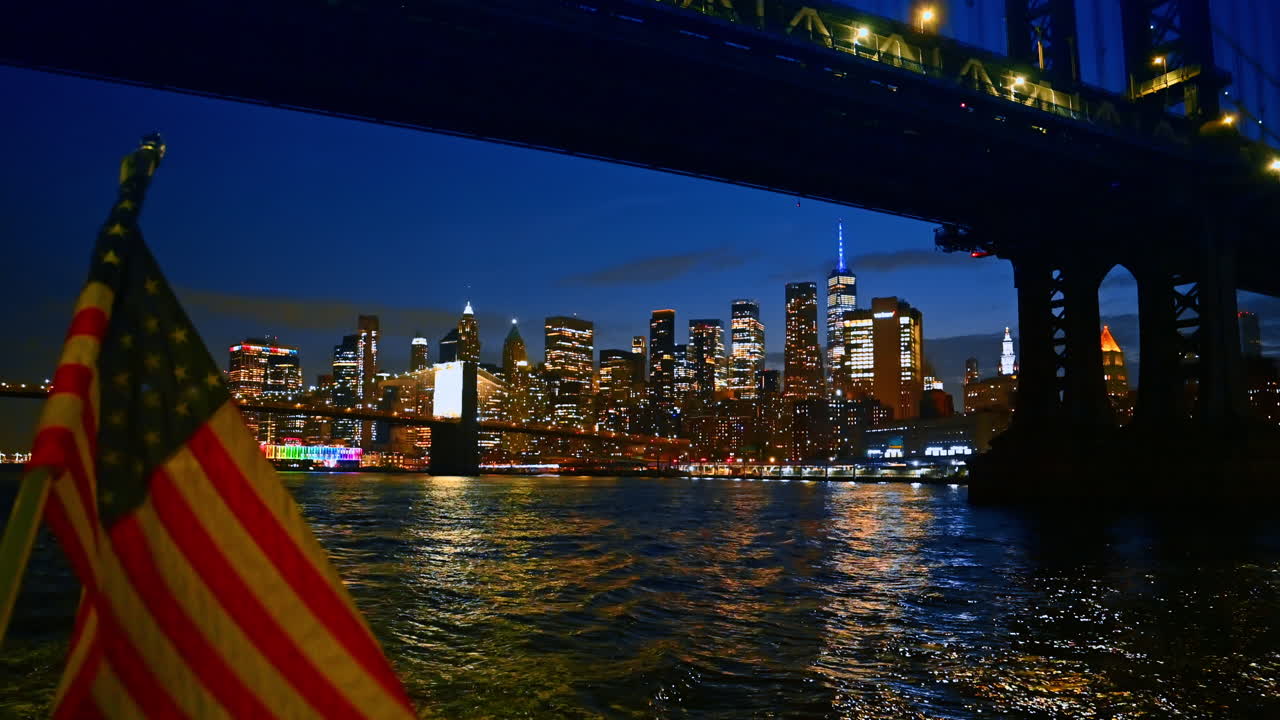 Viaggio in barca lungo l’East River sotto il Manhattan Bridge. Abbacinante skyline notturno di New York sullo sfondo
