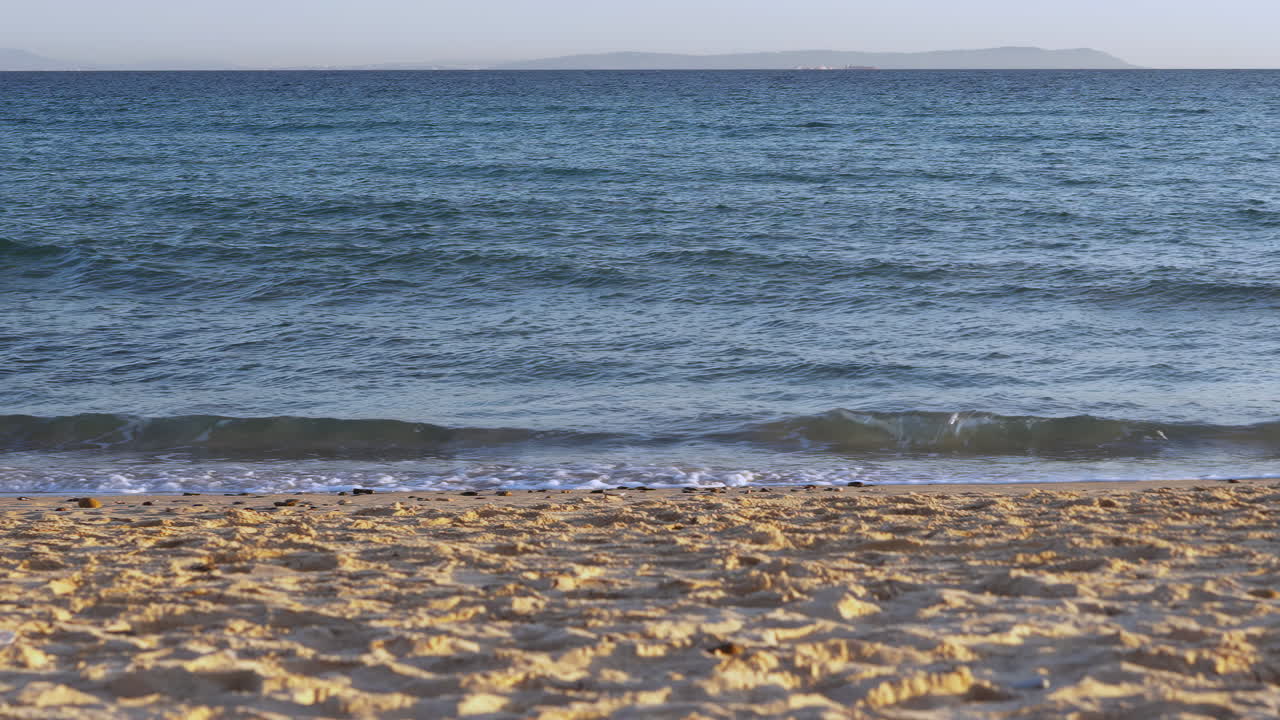 Empty beach with waves hitting the shore in slow motion
