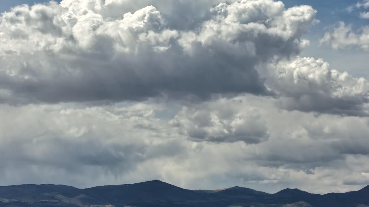 Dynamic drone timelapse follows the convective motion of a monsoonal build-up. The stormy clouds shift rapidly above a remote southwest mountain range, providing an intense meteorological background
