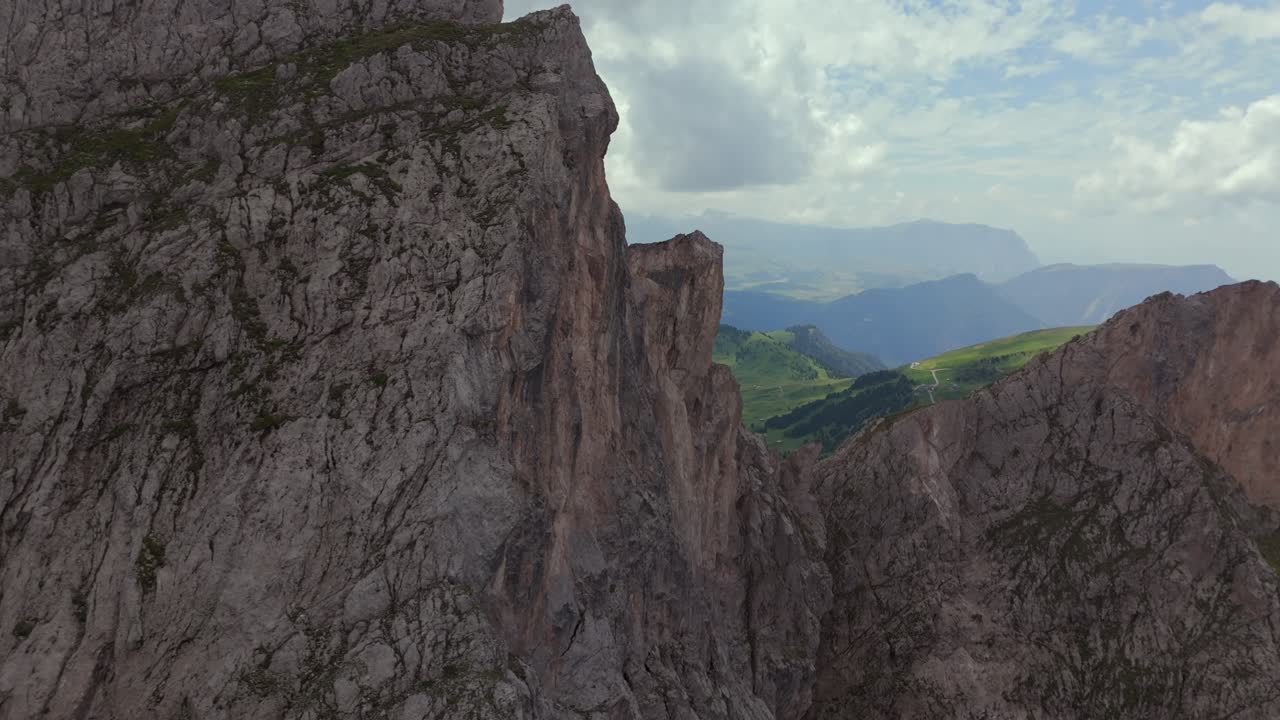 impresionantes imágenes aéreas que muestran los dramáticos acantilados rocosos y los extensos valles verdes de las dolomitas, italia, bajo un cielo parcialmente nublado
