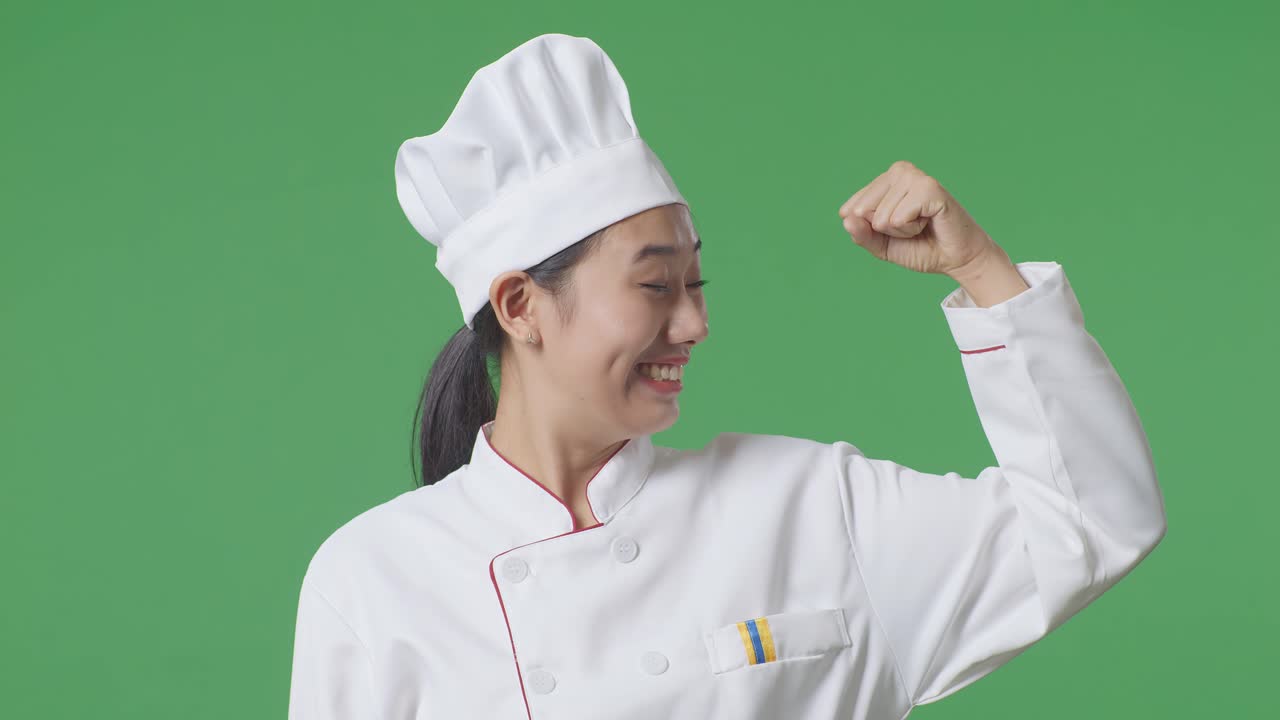 녹색 스크린 배경 스튜디오에 서서 미소 짓고 팔꿈치를 구부리는 아시아 여성 셰프의 클로즈업