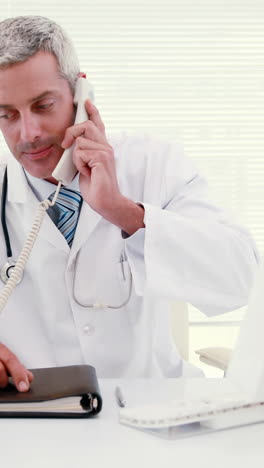 el médico llamando y usando la computadora