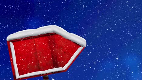 Snow-falling-over-red-wooden-sign-post-against-blue-background