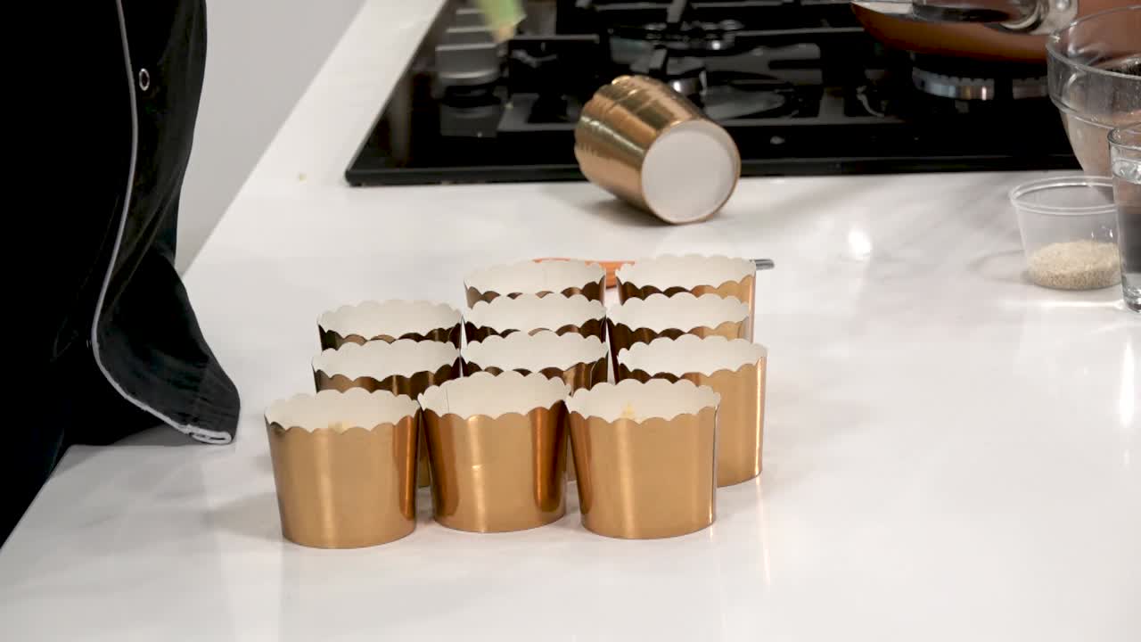 A man filling baking cup with thick dough, close up. A chef uses a pastry bag to make individual cupcakes, filling disposable molds with dough