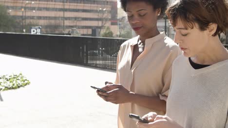 Relaxed-young-women-talking-while-walking-on-street