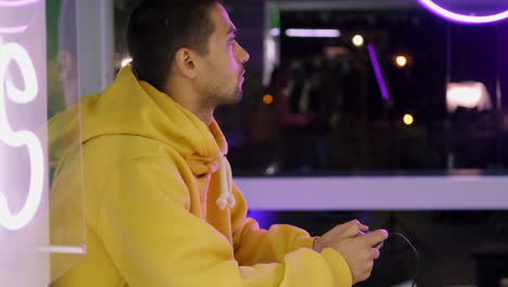 man playing video games in a neon lit arcade