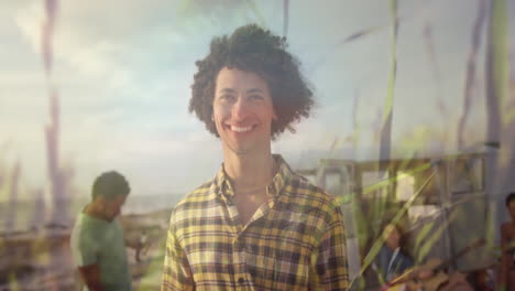 animación de un hombre biracial sonriente con amigos en la playa sobre la hierba