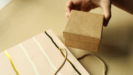 saca una caja de regalos azul de una bolsa de compras
