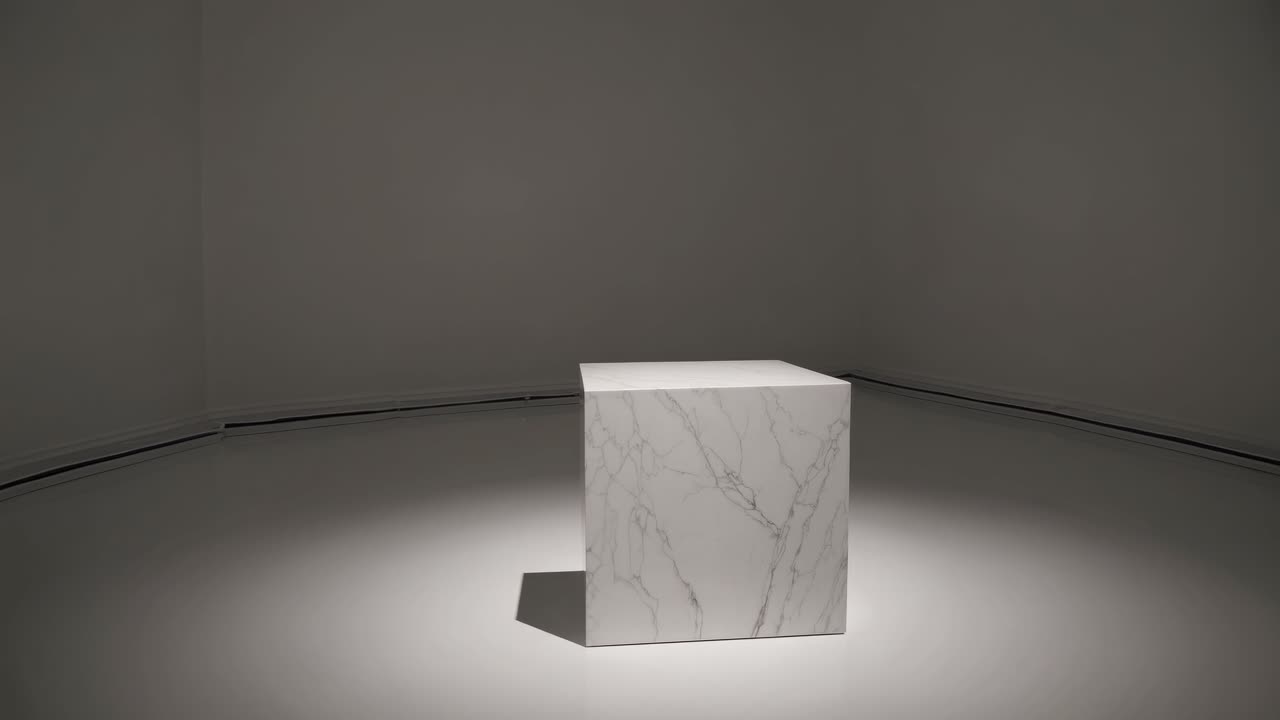 Minimalistisk videokoncept med en marmorkube i et svagt oplyst rum