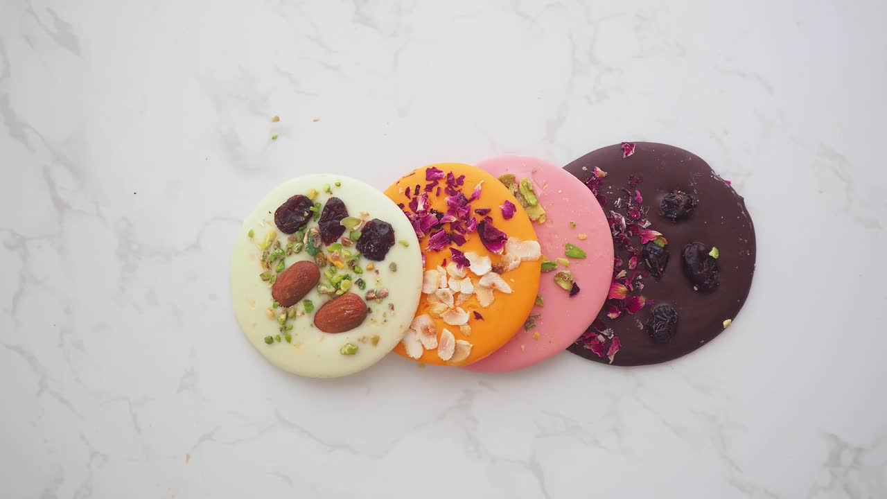 Mano che raccoglie un disco di cioccolato gourmet colorato da una superficie di marmo.