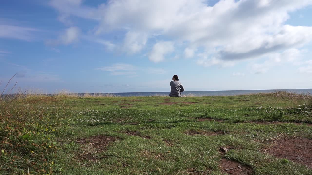 mujer caminando y sentada en un acantilado