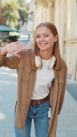 Caucasian-woman-smiling-friendly-at-camera,-hello-waving-hands-gesturing-hi,-greeting-on-city-street