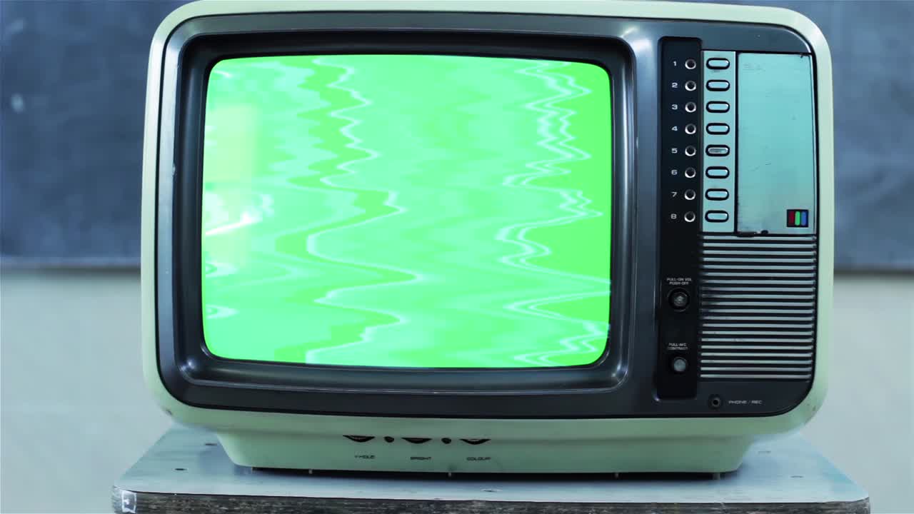 Green screen di una televisione retrò che esplode all'interno di un'aula. Primo piano. 4K.
