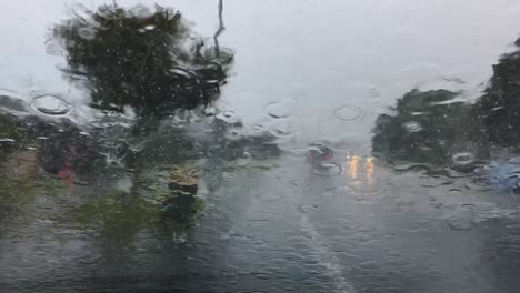 heavy rain falls on car windscreen as other vehicles pass