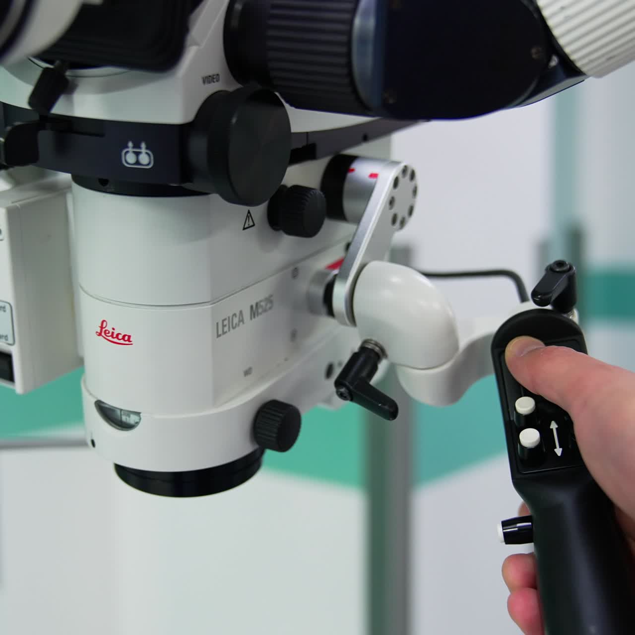 New advanced equipment in surgery room. Male hand taking a handle of powerful microscope in modern surgery room. Close up