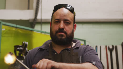 caucasian male factory worker at a factory standing in a workshop, holding an ignited welding gun