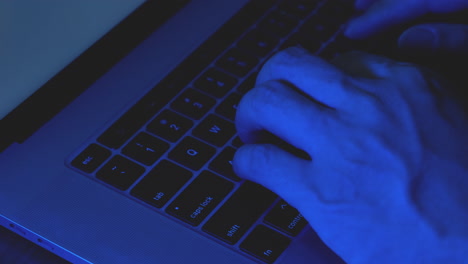 close-up hands of hacker typing code on laptop keyboard