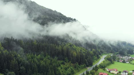 Antena-De-Brumoso-Pueblo-De-Montaña-En-Los-Alpes-Junto-A-Un-Enorme-Bosque