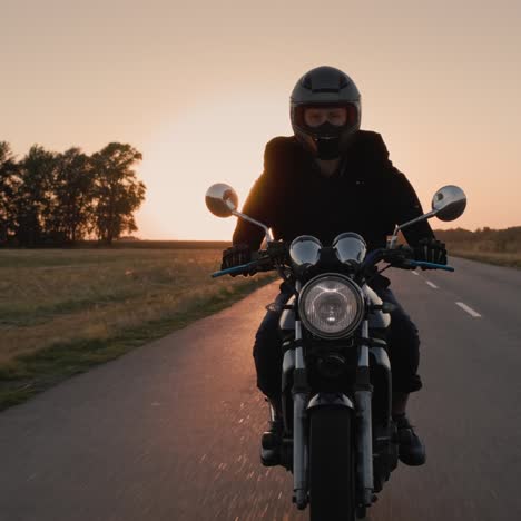 biker riding in the rays of the setting sun on the highway