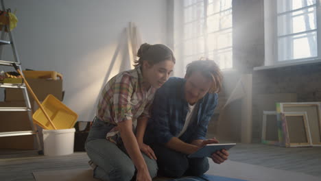 joyful family sitting in new house. couple searching home design on tablet.