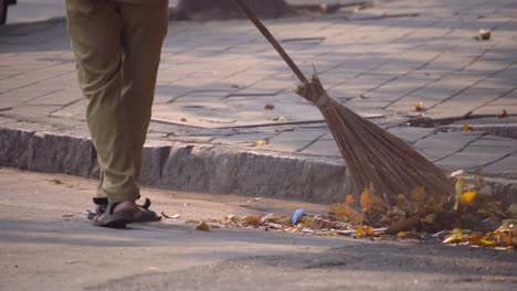 Männlicher-Stadtarbeiter-Der-Straßenreinigung-In-Uniform-Fegt-Den-Bürgersteig-Mit-Einem-Besen-Im-Alten-Mumbai.-Männlicher-Stadtarbeiter-Der-Straßenreinigung-In-Uniform-Fegt-Den-Bürgersteig-Mit-Einem-Besen-Im-Alten-Mumbai