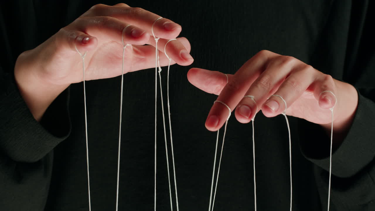 Close-up of Hands Manipulating Strings Like a Puppeteer