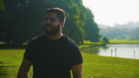 Young-man-walking-at-a-park-near-the-lake-enjoying-life