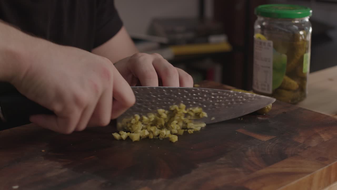 Chopping pickles on wooden cut board with kitchen knife