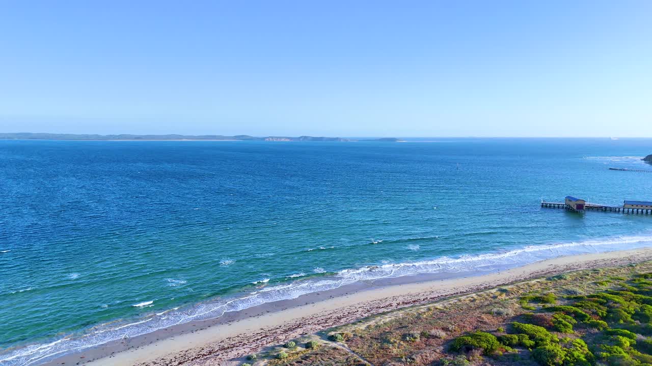 Aerial footage of Bellarine Peninsula's coastline with clear skies, vibrant greenery, and a tranquil pier. Captured in bright daylight
