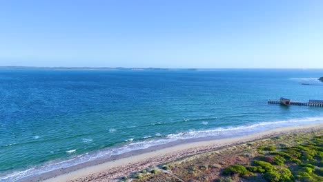 aerial footage of bellarine peninsula's coastline with clear skies, vibrant greenery, and a tranquil pier. captured in bright daylight