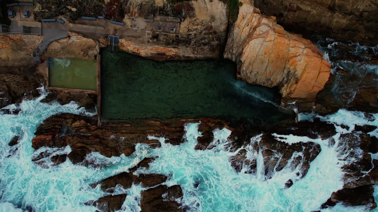 Drone in ascesa di onde azzurre che si infrangono alla Bermagui Blue Pool, Australia