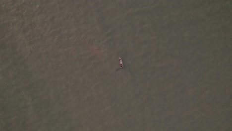 vista de arriba hacia abajo de un pequeño barco de pesca pescando en el agua