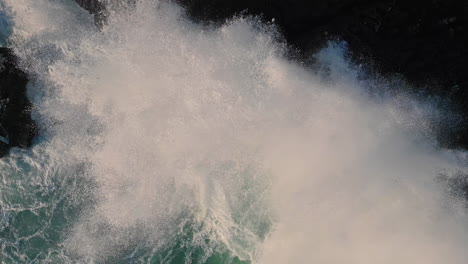 top view foaming ocean hitting coastal rock making bubbling foam in slow motion