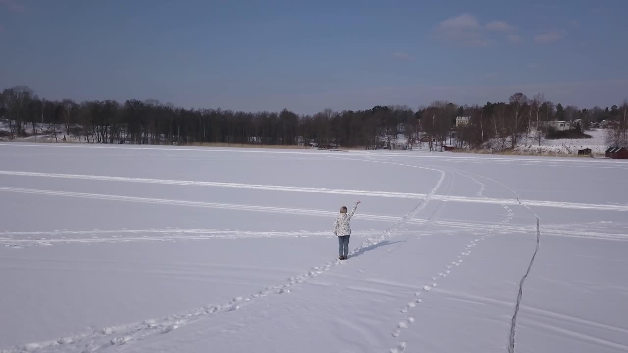 매일 산책하러 가는 동안 큰 호수 반대편에 있는 누군가에게 손을 흔드는 행복한 여성